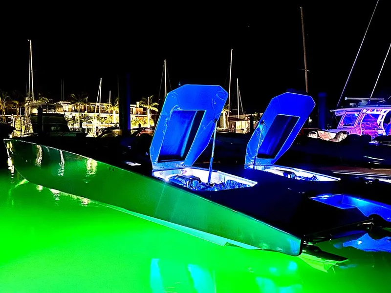 Slide: The Image of Illuminated Skater 46 boat with open hatches, glowing green water at night. - 6
