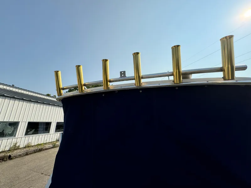 Slide: The Image of 1996 Bayliner 2452 Ciera Express Hardtop with gold rod holders, blue cover, and sunny sky. - 14