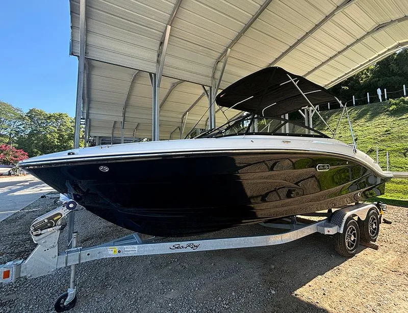 The Image of 2025 Sea Ray SPX 210 boat on trailer under a canopy, side view. - 0
