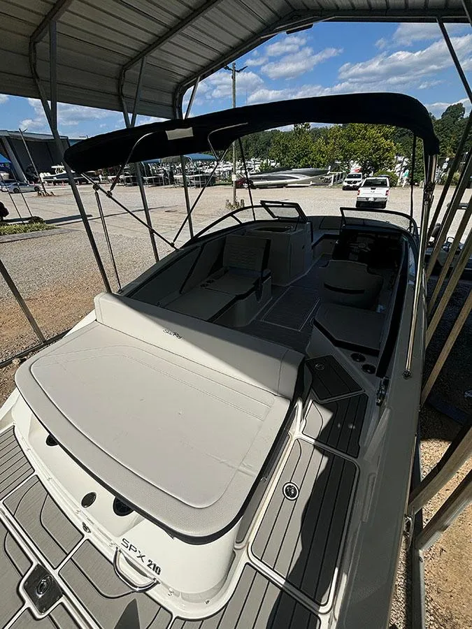 Slide: The Image of 2025 Sea Ray SPX 210 boat under canopy, showcasing sleek design and spacious seating. - 11