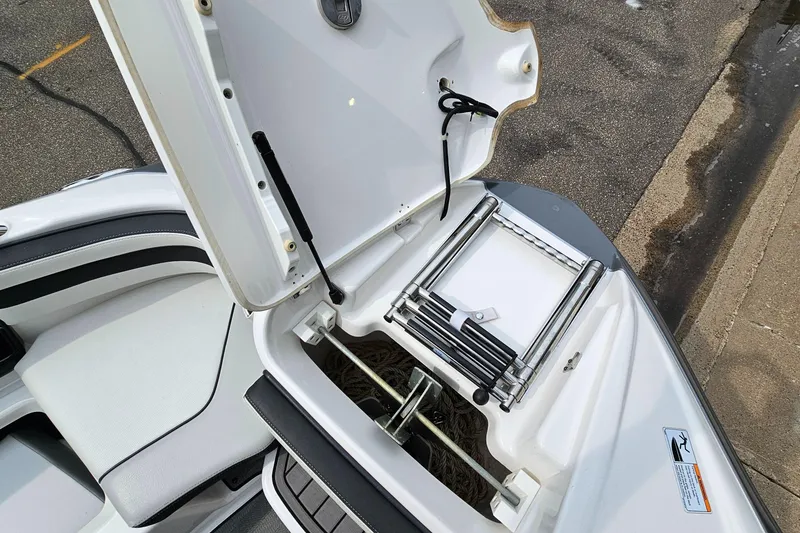 Slide: The Image of Open storage compartment on 2019 Yamaha Boats 242 LIMITED S E SERIES, featuring a retractable ladder. - 24