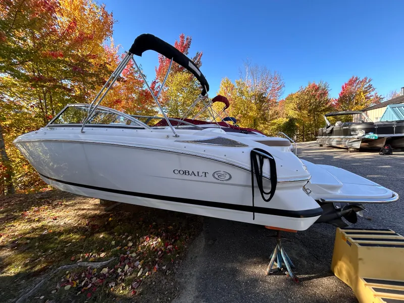 Slide: The Image of 2012 Cobalt 232 Bowrider boat on trailer, surrounded by autumn trees. - 0