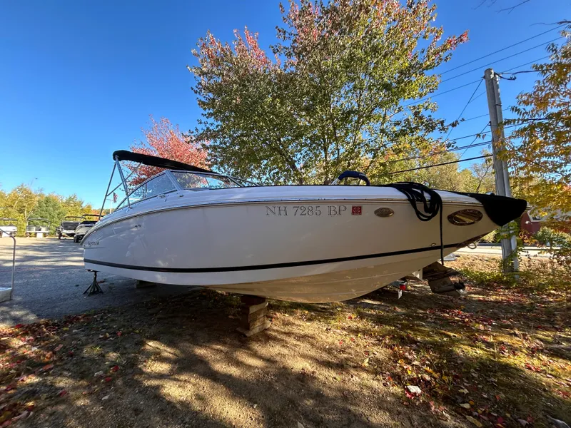 Slide: The Image of 2012 Cobalt 232 Bowrider boat on land, surrounded by autumn trees. - 1