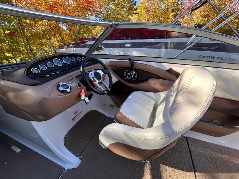 Slide: The Image of 2012 Cobalt 232 Bowrider cockpit with steering wheel and controls, surrounded by autumn foliage. - 16