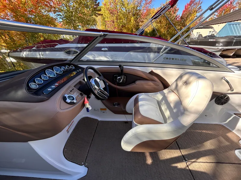 Slide: The Image of 2012 Cobalt 232 Bowrider interior with steering wheel and dashboard, surrounded by autumn foliage. - 22