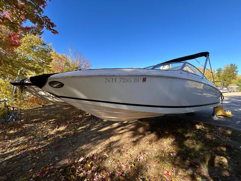 Slide: The Image of 2012 Cobalt 232 Bowrider boat on land, surrounded by autumn trees. - 3