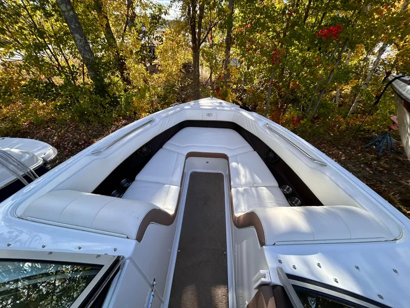 Slide: The Image of 2012 Cobalt 232 Bowrider boat with white seating, surrounded by autumn trees. - 34