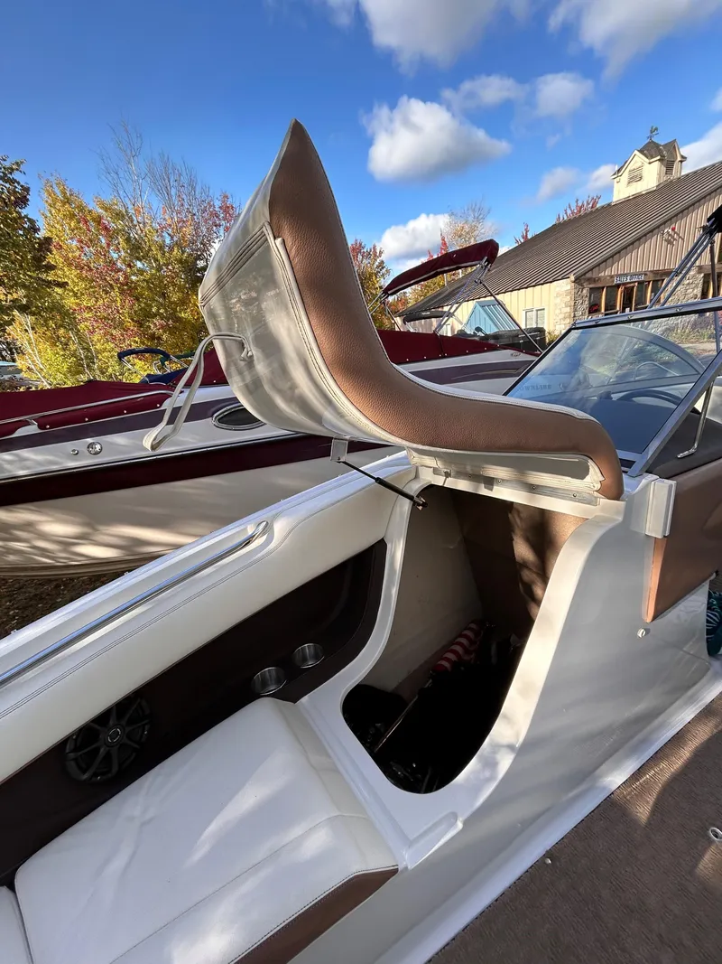 Slide: The Image of 2012 Cobalt 232 Bowrider boat interior with brown and white seating under a blue sky. - 39