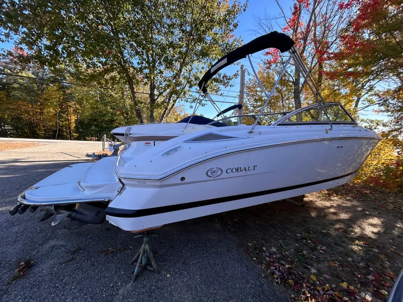 Slide: The Image of 2012 Cobalt 232 Bowrider boat on display, surrounded by autumn trees. - 4