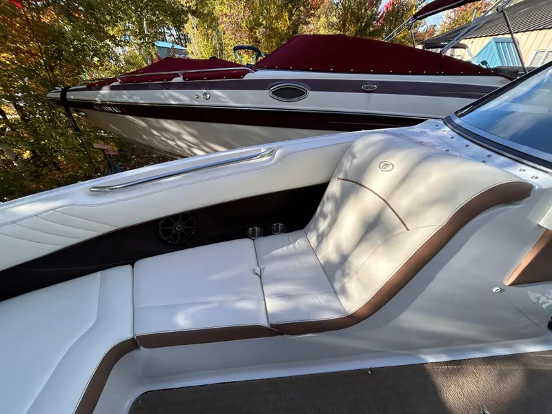 Slide: The Image of 2012 Cobalt 232 Bowrider interior with white and brown seating, parked near another boat. - 40