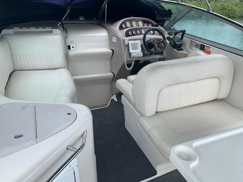 Slide: The Image of 2006 Monterey 302 Cruiser interior with white seating and control panel, docked by water. - 6