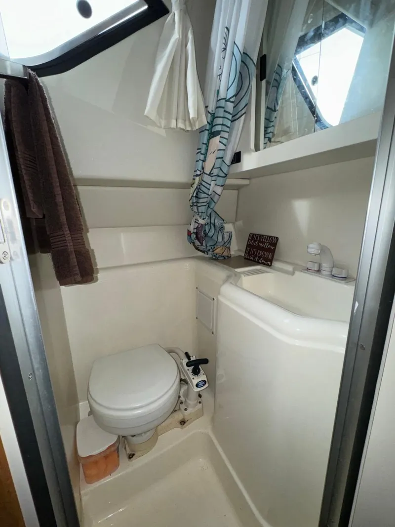 Slide: The Image of 2005 Bayliner 288 Classic boat bathroom with toilet, sink, and window. - 13