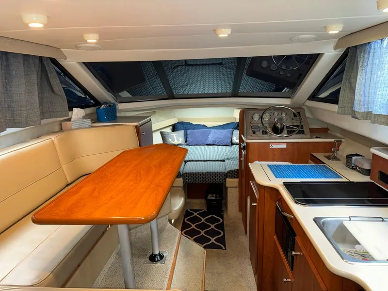 Slide: The Image of 2005 Bayliner 288 Classic interior with dining area, kitchenette, and cozy sleeping space. - 3
