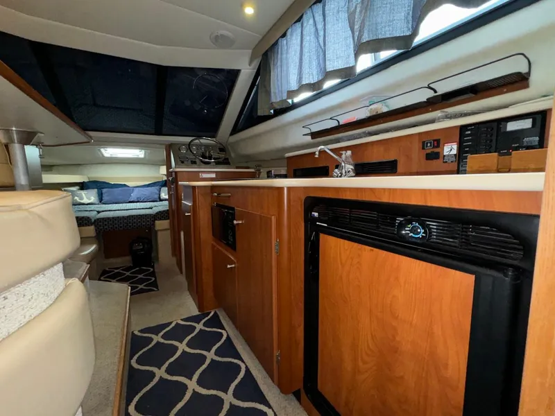 Slide: The Image of Interior of 2005 Bayliner 288 Classic boat, featuring kitchen area with wood cabinetry and appliances. - 6