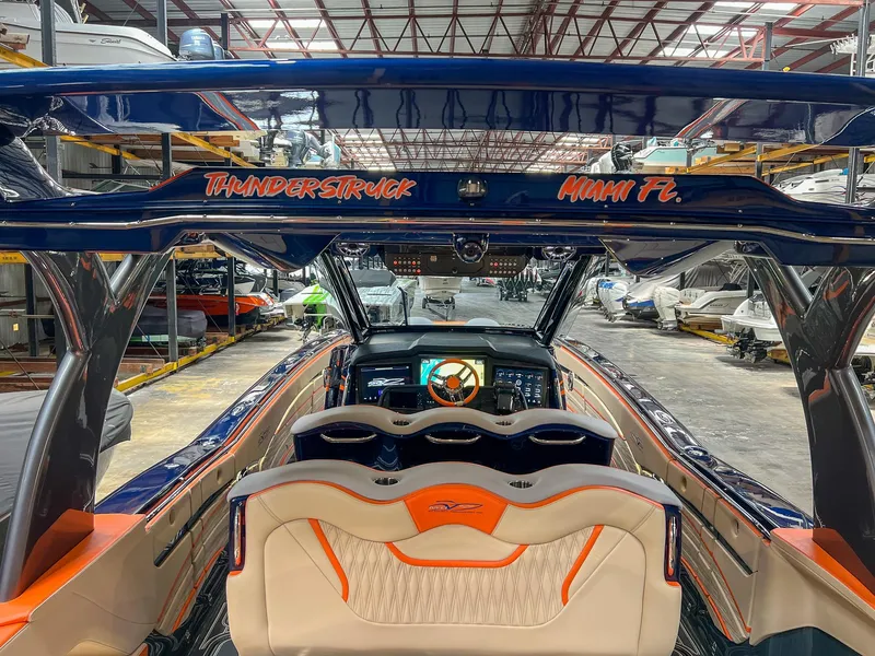 Slide: The Image of 2024 MTI V42 boat interior with orange and white seating, located in a warehouse. - 16