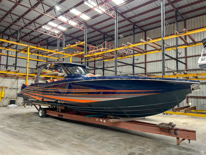 Slide: The Image of 2024 MTI V42 boat in warehouse, sleek design with orange and blue accents. - 24