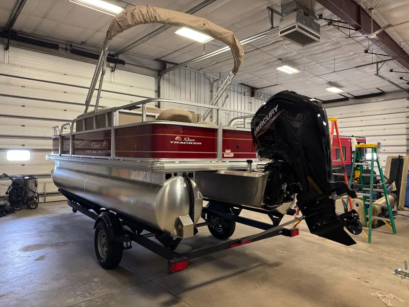 Slide: The Image of 2025 Sun Tracker Bass Buggy 18 DLX pontoon boat in a garage setting. - 2