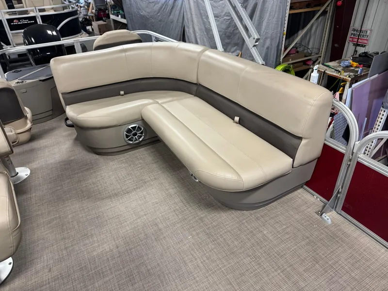 Slide: The Image of 2025 Sun Tracker Bass Buggy 18 DLX pontoon boat interior with beige seating and speaker. - 7