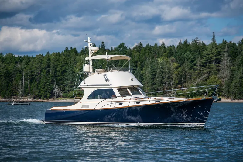 Slide: The Image of 2006 Hinckley Talaria 44 FB yacht cruising on a scenic lake with forested background. - 1