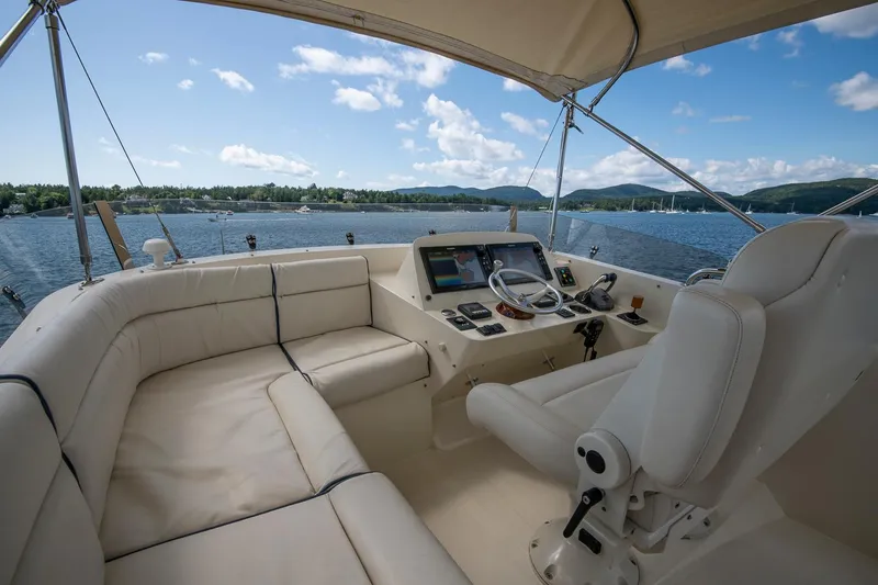 Slide: The Image of 2006 Hinckley Talaria 44 FB yacht cockpit with helm, white seating, and scenic water view. - 15