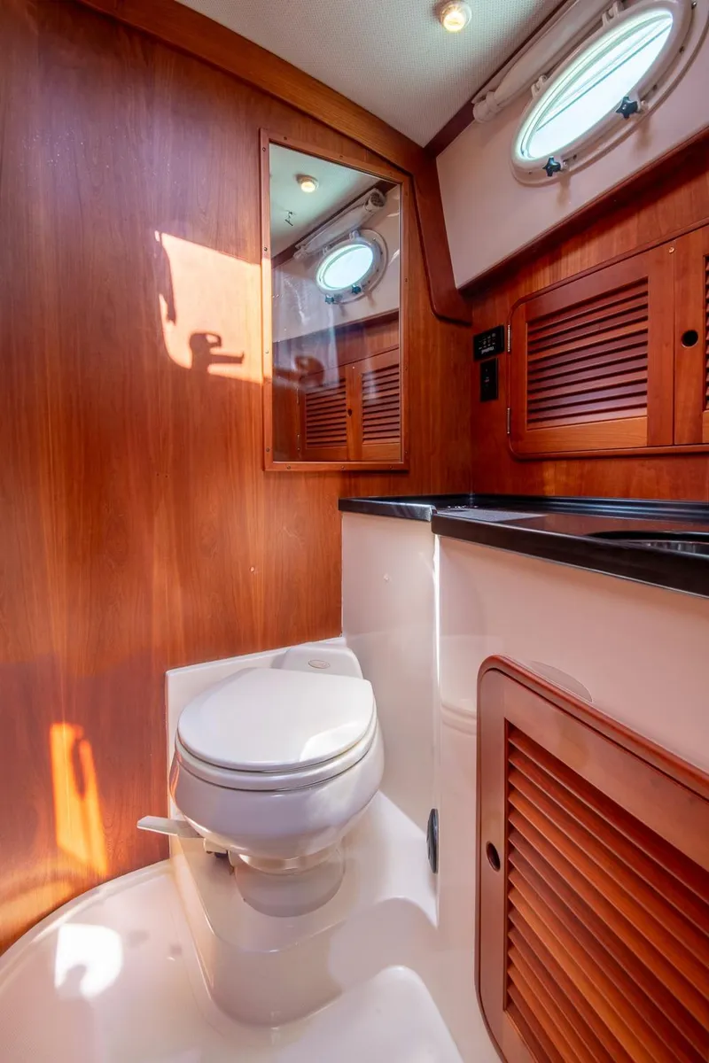 Slide: The Image of 2006 Hinckley Talaria 44 FB yacht bathroom with wooden cabinetry and porthole window. - 45