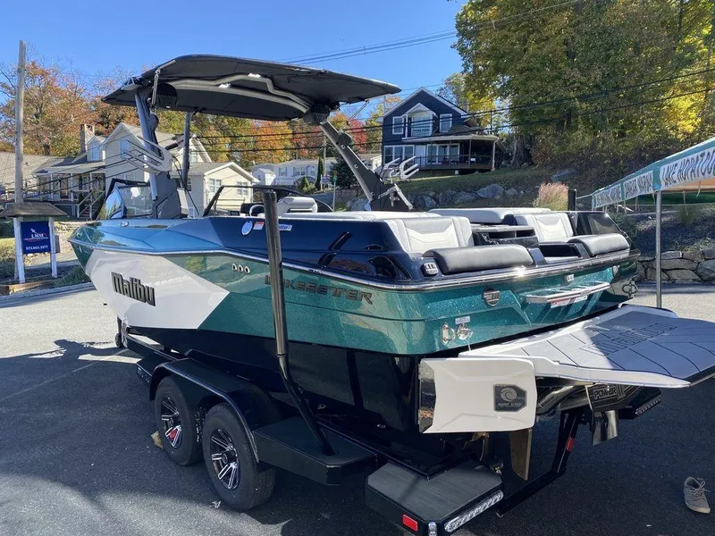 Slide: The Image of 2025 Malibu 23 LSV boat on trailer, parked outdoors, showcasing sleek design and vibrant colors. - 5