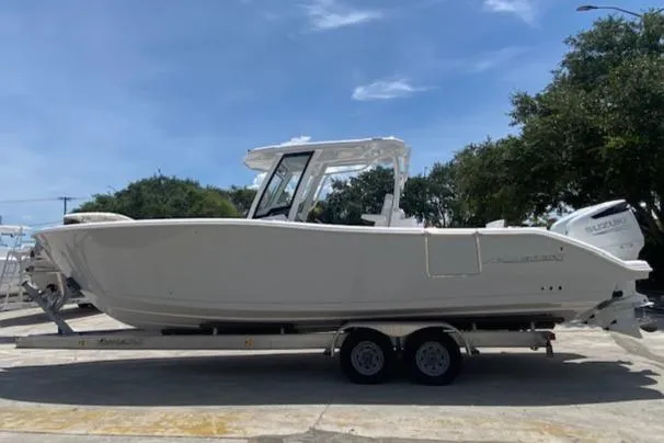 The Image of 2025 Aquasport 2800 AS boat on trailer, parked outdoors under clear sky. - 1