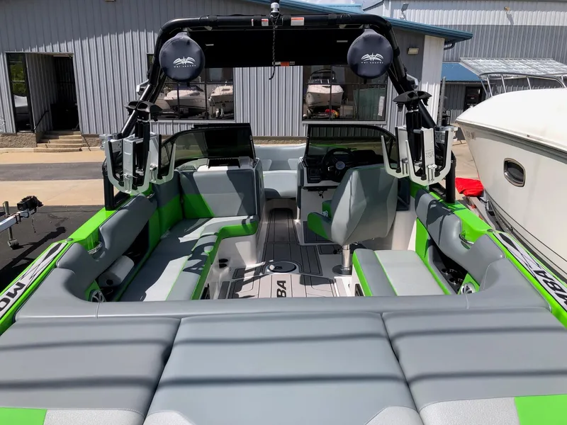 Slide: The Image of 2018 Moomba Max boat interior with green and gray seating, docked outdoors. - 7