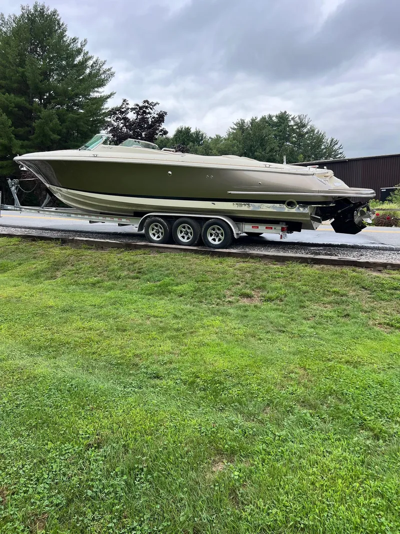 Slide: The Image of 2014 Chris-Craft 32 Launch boat on trailer, parked on grass under cloudy sky. - 10