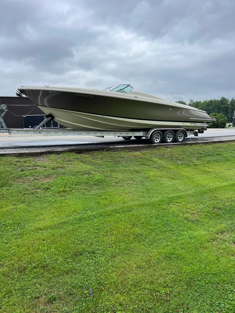 Slide: The Image of 2014 Chris-Craft 32 Launch boat on trailer, parked on grass under cloudy sky. - 11