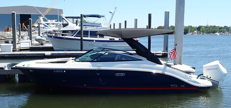 Slide: The Image of 2024 Sea Ray SLX 260 Outboard boat docked at marina, featuring sleek design and American flag. - 1