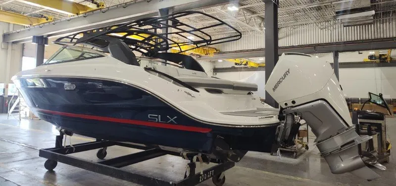 Slide: The Image of 2024 Sea Ray SLX 260 Outboard boat in a warehouse setting. - 2