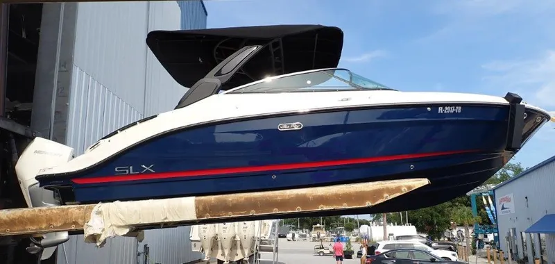 Slide: The Image of 2024 Sea Ray SLX 260 Outboard boat in marina, blue and white design. - 4