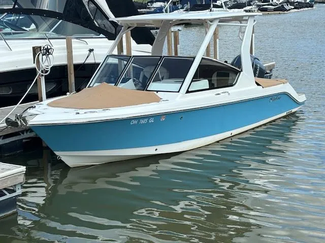 Slide: The Image of 2023 Edgewater 230 CX boat docked in marina, blue and white design. - 1