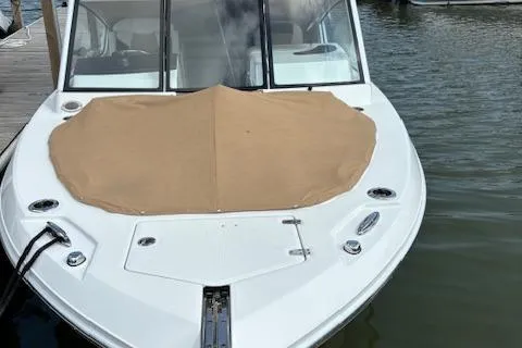 Slide: The Image of 2023 Edgewater 230 CX boat docked with tan cover on bow. - 11