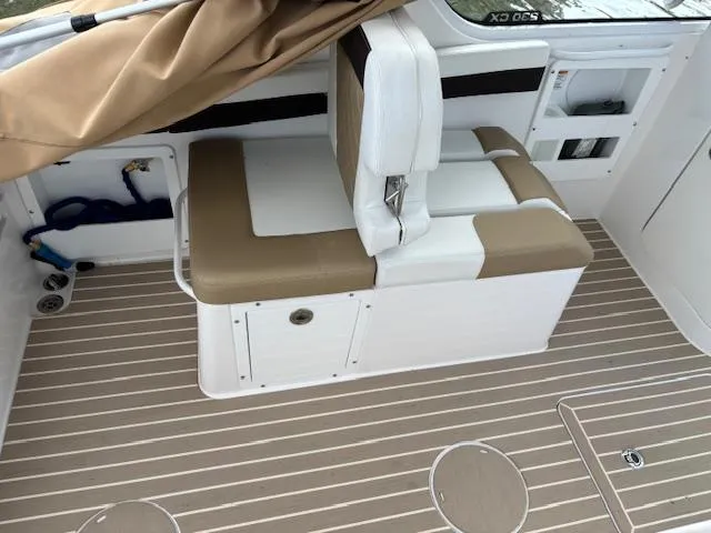 Slide: The Image of 2023 Edgewater 230 CX boat interior with beige seating and striped flooring. - 12