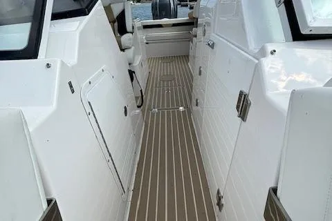 Slide: The Image of 2023 Edgewater 230 CX boat interior with sleek white design and wood-textured flooring. - 14