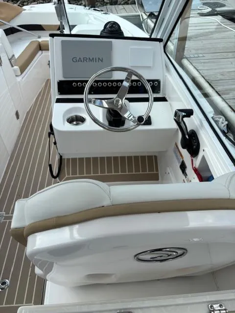 Slide: The Image of 2023 Edgewater 230 CX boat cockpit with Garmin navigation system and steering wheel. - 2