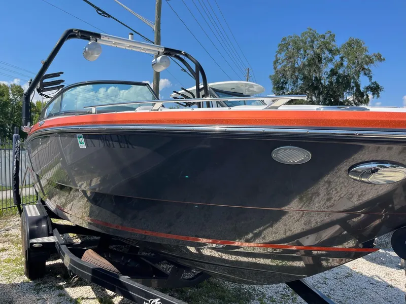 The Image of 2018 Monterey 238 Surf boat on trailer, black and orange design, sunny day. - 0