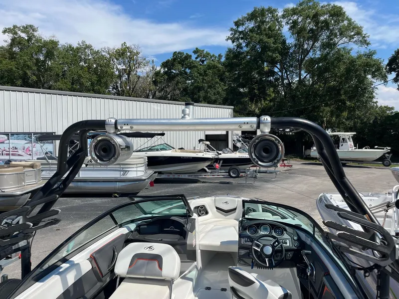 Slide: The Image of 2018 Monterey 238 Surf boat interior with speakers, parked near other boats. - 6