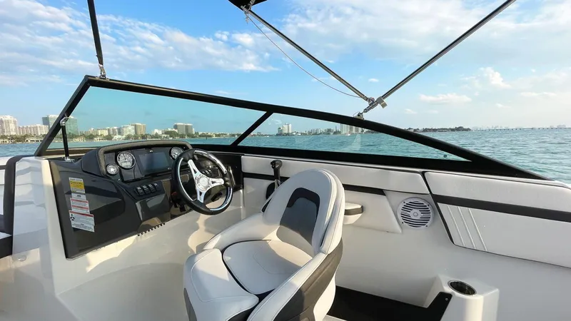 Slide: The Image of 2021 Monterey M225 boat interior with steering wheel, dashboard, and seating on open water. - 5
