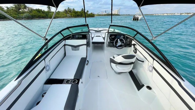 Slide: The Image of 2021 Monterey M225 boat interior on calm blue water, featuring sleek seating and steering area. - 6