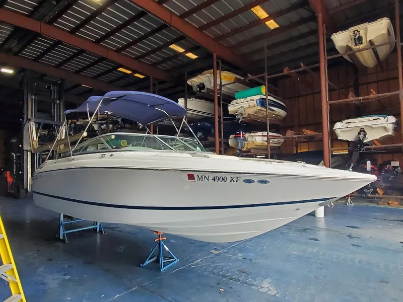 Slide: The Image of 2007 Cobalt 240 boat in storage facility, elevated on stands, with other boats in background. - 2