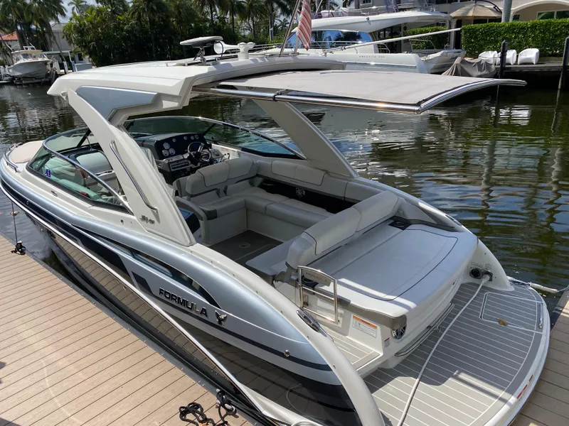 Slide: The Image of 2021 Formula 310 Bowrider I/O boat docked by a serene waterfront. - 4