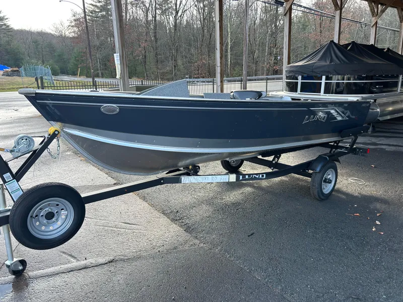 Slide: The Image of 2025 Lund Fury 1400 Tiller boat on trailer, parked outdoors. - 0
