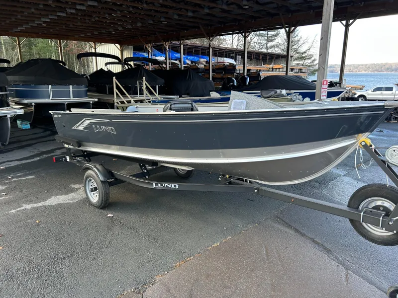 Slide: The Image of 2025 Lund Fury 1400 Tiller boat on trailer in covered storage area. - 1