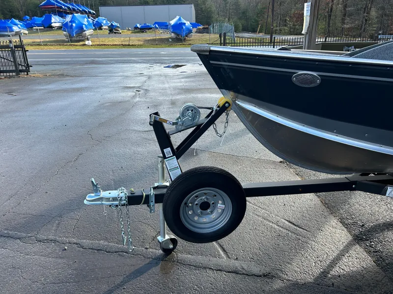 Slide: The Image of 2025 Lund Fury 1400 Tiller boat on trailer in parking lot. - 3