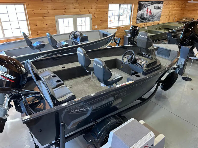 Slide: The Image of 2025 Lund Rebel XL 1650 XL SS fishing boat in showroom, featuring Mercury engine. - 6