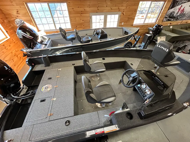 Slide: The Image of 2025 Lund Rebel XL 1650 XL SS fishing boat in showroom, featuring spacious seating and modern controls. - 8