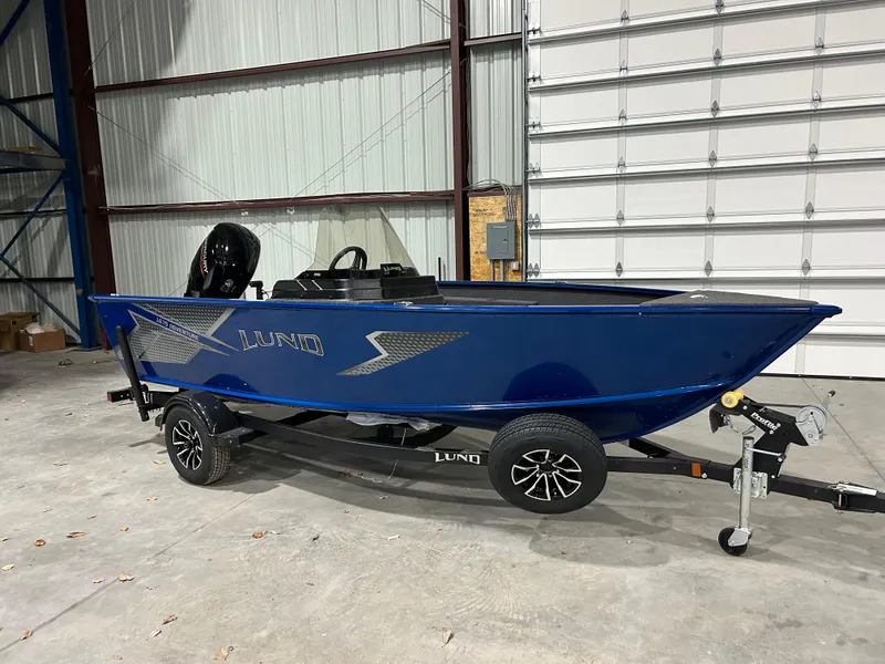 Slide: The Image of 2025 Lund ADVENTURE 1675 SS boat in a warehouse, blue exterior, on a trailer. - 2